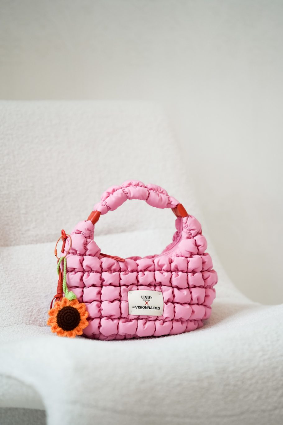 Pinke geflochtene Handtasche von Unio x Les Visionnaires mit gehäkeltem Sonnenblumen-Anhänger.