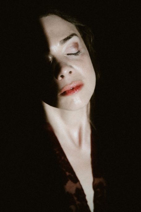 Intimes Boudoir-Porträt einer Frau mit geschlossenen Augen, deren Gesicht von weichem Licht und tiefen Schatten gezeichnet wird.