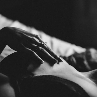 Luxe Boudoir Detailaufnahme einer Frau in schwarzer Spitzenunterwäsche mit Ringen an den Händen im dunklen Licht